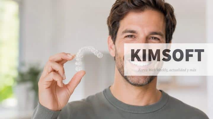 Persona sonriendo mientras sostiene un alineador transparente de ortodoncia invisible